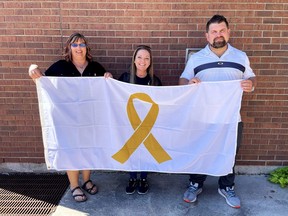Acting Mayor Anthony Ceccacci, right, is joined in holding a flag for Childhood Cancer Awareness month with Anita Betterley, left, and Lorraine Jewell, middle, during a flag-raising ceremony at the Civic Centre Sept. 2. (Handout/Postmedia Network)