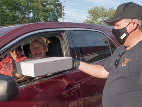 Harry and Janice Kemp of St. Marys pick up dinner from firefighter Phil West on Saturday. The St. Marys Fire Department –  in partnership with Joe’s Diner and Broken Rail Brewing – handed out $25 pork chop dinners drive-thru style, raising money for charity. Chris MontaniniStratford Beacon Herald