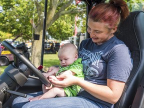 Kaitlyn holds her 3-month-old baby Carson as he touches the wheel of a piece of farm equipment during the Touch a Truck event on Saturday in Belleville, Ontario. ALEX FILIPE