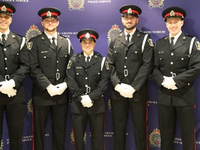 The six new constables joining the greater sudbury police stand in a row wearing their dress uniforms in from of a purple backdrop