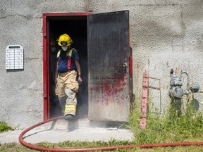 A Firefighter exits a smoking Fire Fighter Training Tower during Camp Molly, a training camp aimed at teaching young women the skills needed to be a Firefighter. ALEX FILIPE