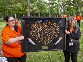 Brittany Powless (left) of the Brantford Region Indigenous Support Centre, and Sherlene Bomberry, a survivor of the Mohawk Institute residential school unveiled artwork depicting 215 orange shirts during the Honouring Our Children Social on Friday at Mohawk Park in Brantford.