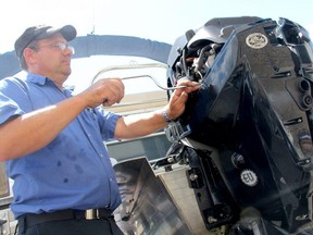 Marine technician John Ptaszynski of Maple City Marine in Chatham tunes up a boat engine. Photo taken July 12, 2013. Postmedia file photo