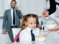 selective focus of kid in school uniform at table with breakfast and mother pouring milk into bowl with crunches at home, back to school concept