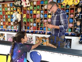 Real Vachon, who works for Billy G Amusements, showed 8-year-old Darian Hill the small stuff moose she won at the balloon popping game booth during the Six Nations Fall Fair Saturday.