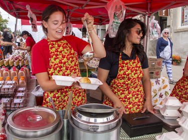 Grace Adams (left) and Harshni Patel serve up apple dumplings drizzled with warmed caramel sauce at the Brantwood Farms booth on Sunday September 18, 2022 during Apple Fest in St. George, Ontario. Brian Thompson/Brantford Expositor/Postmedia Network
