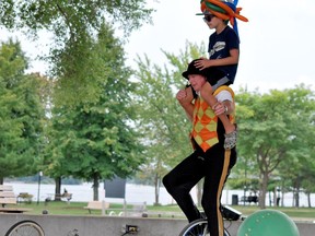 With the help of a young assistant, Circus Johnathan unicycles around the amphitheatre at Joel Stone Heritage Park on Sunday afternoon as part of entertainment for the 1000 Islands Waterfront Festival. The festival concluded Sunday. (KEITH DEMPSEY/Local Journalism Initiative Reporter)
