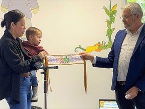 From left, Kelly Back (Christopher Thompson's sister) holds her son and gives ACCFutures executive director Greg Pietersma a beaded friendship belt she created that will honour Thompson's contributions to the organization. Handout/Cornwall Standard-Freeholder/Postmedia Network