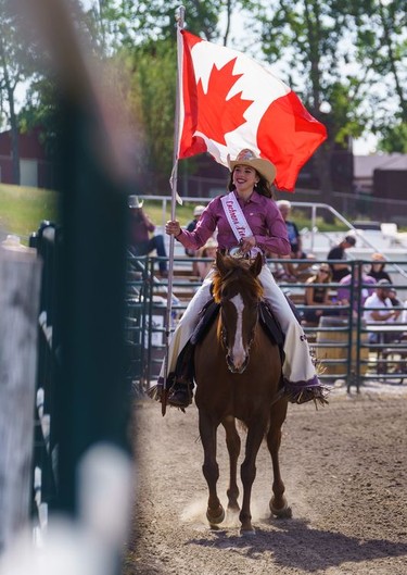 A rider holds a Canadian flag at the Lions Club rodeo in Cochrane on Monday, Sept. 5, 2022.