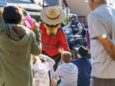 The RCMP mascot high fives a child at the labour day parade in Cochrane on Monday, Sept. 5, 2022.