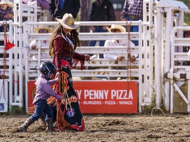 A young boy walks off with a girl after mutton bustin' at the Lions Club rodeo in Cochrane on Monday, Sept. 5, 2022.