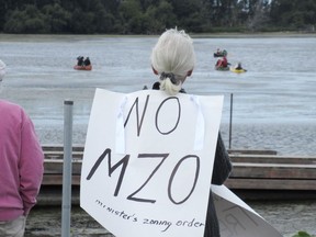 A protester holds a sign against city council pursuing a provincial ministerial zoning order to allow the development of a wetland on the former Davis Tannery site during a demonstration by people in canoes and kayaks on the Cataraqui River in Kingston on Monday.