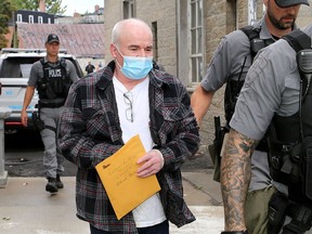 Michael Wentworth is led into the Frontenac County Court House for the first day of a trial for historical murder and robbery charges, among other charges, on Tuesday.