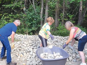 Photo by Jacqueline Rivet
Youngest volunteer, Jayce with his grandmother Carol Champagne-McKinley and volunteer Dave Morley hard at work loading large rocks in the wheelbarrows. For the Story, see page 2.