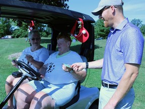 Former Sarnia Sting player Jamie Fraser buys raffle tickets from volunteers Pat Sterling and Lynn LeFaive during the team's fundraising golf tournament for Pathways Health Center for Children on Saturday at Huron Oaks Golf Course in Bright's Grove.  Terry Bridge/Sarnia Observer/Postmedia Network