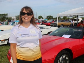 Alissa Hudy, director of the eastern region for Enbridge, stands next to some of the entries in Saturday's car show hosted by the company in Sarnia to raise money for the United Way of Sarnia-Lambton.