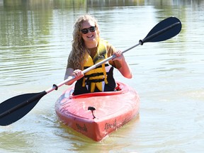 Kelsey Nydam, executive director of the Downtown Wallaceburg BIA, takes one of the kayaks from the new Whimsies Paddle Adventure rental service onto the Sydenham River Sept. 1, 2022. (Tom Morrison/Chatham This Week)