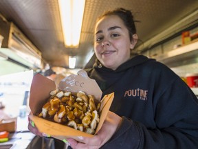 Paige Lavergne holds a steaming portion of freshly made poutine inside a food truck during the Quinte West Poutine Feast on Saturday in Trenton, Ontario. ALEX FILIPE
