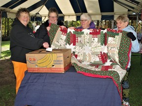 From left: Ruth Lagassie, Cassandra Lagassie, Powassan and District Food Bank coordinator Diane Cole and longtime food bank volunteer Betty Leblanc display the Christmas quilt the mother-and-daughter Lagassie team made for the food bank as a fundraiser. Ruth Lagassie drew the name of the winner of the quilt.
