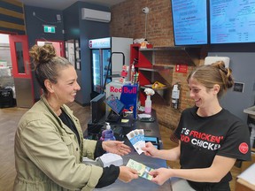 Elizabeth Costa-Alves purchases the first ticket to the Crow Your Boat race from Emily Meko at Loaded 2 Go restaurant. (Handout/Postmedia Network)