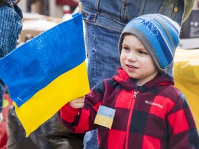 A boy waves a felt Ukrainian flag he made during fundraising efforts held in March by Humanity for Free Ukraine in Belleville, Ontario. ALEX FILIPE