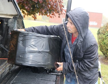 Ricci Burton adjusts a speaker covered due to the rain before a rosary rally at Our Lady of Fatima grotto at Our Lady of Good Counsel Catholic Church in Sault Ste. Marie, Ont., on Saturday, Oct. 15, 2022. (BRIAN KELLY/THE SAULT STAR/POSTMEDIA NETWORK)