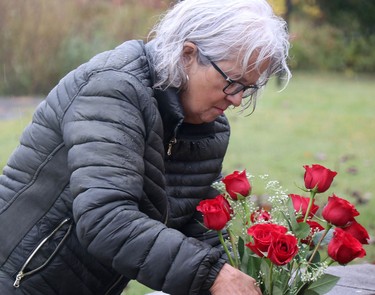Organizer Claudette Breton presents roses in the rain before a rosary rally at Our Lady of Fatima grotto at Our Lady of Good Counsel Catholic Church in Sault Ste. Marie, Ont., on Saturday, Oct. 15, 2022. (BRIAN KELLY/THE SAULT STAR/POSTMEDIA NETWORK)
