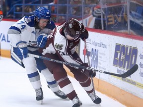Jacob Holmes (74) of the Sudbury Wolves battles for the puck with Chase Stillman (21) of the Peterborough Petes during OHL action at Sudbury Community Arena on Sunday, October 16, 2022.