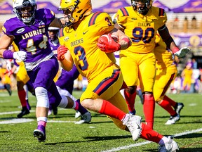 Queen’s Gaels receiver Aidan O’Neal carries the ball upfield as Laurier Golden Hawks' Taylor Stalkie chases. Looking on is Queen’s Darien Newell during the Gaels' 30-11 Ontario University Athletics football win over the Laurier in Waterloo on Saturday.
