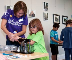 Librarian Krista Robinson offers Rosa Merkel a hand making a button at the Stratford Public Library on Saturday.  Button making was one of the activities organized for the fifth anniversary of the library's MakerSpace.  Chris Montanini/Stratford Beacon Herald