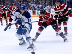 Nick DeGrazia (16) of the Sudbury Wolves handles a puck while being pursued by Henry Mews (11) of the Ottawa 67's during OHL action at Sudbury Community Arena on Sunday, October 23, 2022.