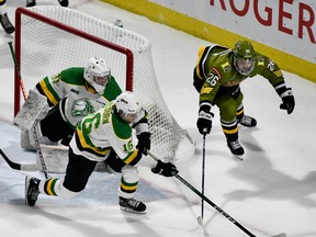 Sean McGurn of the London Knights clears the puck from goaltender Zach Bowen's crease as Kyle Jackson of the visiting North Bay Battalion looks to steal the disc in their Ontario Hockey League game Friday night. The Troops played the middle game of a three-game road trip.
