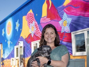 Nancy Ruiz and her dog Monika stand in front of the new Indigenous mural in the 10th Street parking lot in Canmore. photo by Pam Doyle/www.pamdoylephoto.com