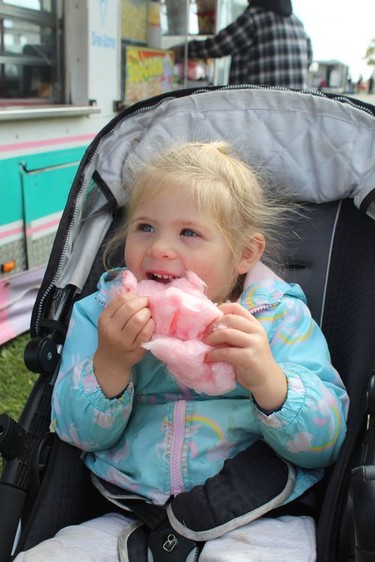 Three-year-old Paige Homewood of Burford takes a big bite of cotton candy at the Burford Fair on Sunday. Michelle Ruby