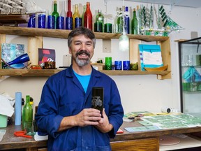 Hugh Moloney poses with the first glass he ever made through cold glasswork at his workshop in Cochrane on Thursday, Sept. 29, 2022.