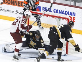 Peterborough Petes forward Tucker Robertson fights for a loose puck in front of Kingston Frontenacs goaltender Ivan Zhigalov and defenceman Ben Roger during the first period of an Ontario Hockey League game on Thursday night in Peterborough.