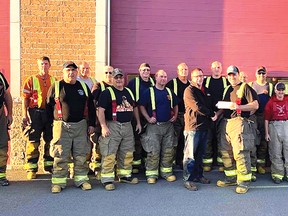 Ryan Courtemanche presented a cheque for $15,900 to Trevor McVey, for Muscular Dystrophy Canada, from the proceeds of their Espanola Firefighters ATV Poker Run, while the rest of the firefighters look on. 
Photo supplied