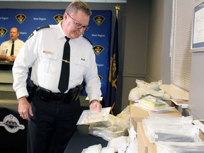 Insp. Chris Avery, Lambton OPP's detachment commander, checks out the evidence seized during a 14-month investigation into drug trafficking in Walpole Island First Nation. Terry Bridge/Sarnia Observer/Postmedia Network