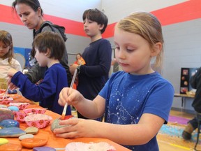 Marigold Williamson, 4, paints a stone Saturday at the Fiery Faces Family Day held at the YMCA Petrolia.