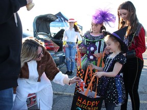 Kim MacGregor, left, hands treats to Amelia Bosley, eight, and her sisters Annalise, five, and Abigail 11, at the Sarnia Street Cruisers' second annual Trunk or Treat event at Hiawatha Horse Park Saturday. (Tyler Kula/ The Observer)