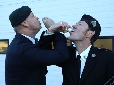 Daryl Adams, left, a veteran and retired Staff Sergeant of the Greater Sudbury Police Service, and piper John Macdonald, of the Greater Sudbury Police Pipe Band, take part in a toast called "Paying the Piper", at a flag-raising ceremony to mark the annual Royal Canadian Legion Poppy Campaign in Sudbury, Ont. on Friday October 28, 2022. A massive poppy flag was raised at the ceremony. John Lappa/Sudbury Star/Postmedia Network