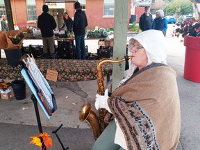 Very bundled up against the morning's six-degree chill, busker Connie Furtney plays tenor sax Saturday at the Horton Farmers' Market. Eric Bunnnell