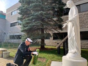 War veteran and Scollard Hall alumni Colin Vezina lays a wreath at the bottom of the statue of Mary and plaque to honour the 31 Scollard Hall students who didn't return from war.