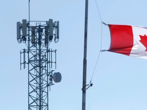 A wireless communications tower stands near a Canadian flag in Belleville, Ont. Similar towers in eastern Ontario are to be upgraded this year, with more built by late 2024, by Rogers Communications Inc.