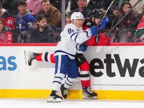Mac Hollowell #81 of the Toronto Maple Leafs checks Yegor Sharangovich #17 of the New Jersey Devils into the boards in the second period at the Prudential Center on November 23, 2022 in Newark, New Jersey. (Photo by Mitchell Leff/Getty Images)