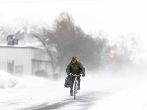 A man rides his bike down the street in Fort Erie, Ont., during an early winter storm that delivered high winds and large amounts of snow across southern Ontario and western New York on Nov. 19. Canadians enjoying a brief relief from the onset of winter-like conditions may want to enjoy the temperatures while they can because The Weather Network is forecasting a colder than normal start to winter across most of the country