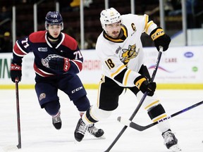 Sarnia Sting captain Nolan Dillingham (18) shoots while being watched by Saginaw Spirit's Michael Misa (77) in the first period at Progressive Auto Sales Arena in Sarnia, Ont., on Friday, Nov. 25, 2022. Mark Malone/Chatham Daily News/Postmedia Network