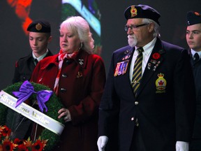 Pastor Robert Parmenter escorts Debbie Pinksen to lay a wreath during Remembrance Day ceremonies at MacDonald Island Park on November 11, 2022. Pinksen’s son, Corporal Brian Pinksen of 2nd Battalion, the Royal Newfoundland Regiment, was killed in Afghanistan on Aug. 30, 2010. Vincent McDermott/Fort McMurray Today/Postmedia Network