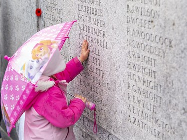 Five-year-old Zofia Borutski touches a wall at the Brant County War Memorial bearing the names of local servicemen who died in wars, following the Remembrance Day service on Friday November 11, 2022 in Brantford, Ontario. Brian Thompson/Brantford Expositor/Postmedia Network