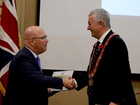 Ontario Municipal Affairs Minister and local MPP Steve Clark, left, shakes hands with outgoing Brockville Mayor Mike Kalivas as he hands Kalivas a certificate recognizing the re-elected councillor's 25 years in municipal politics. (RONALD ZAJAC/The Recorder and Times)